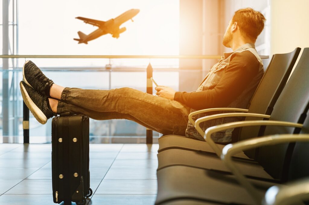 Homem sentado no aeroporto com uma mala