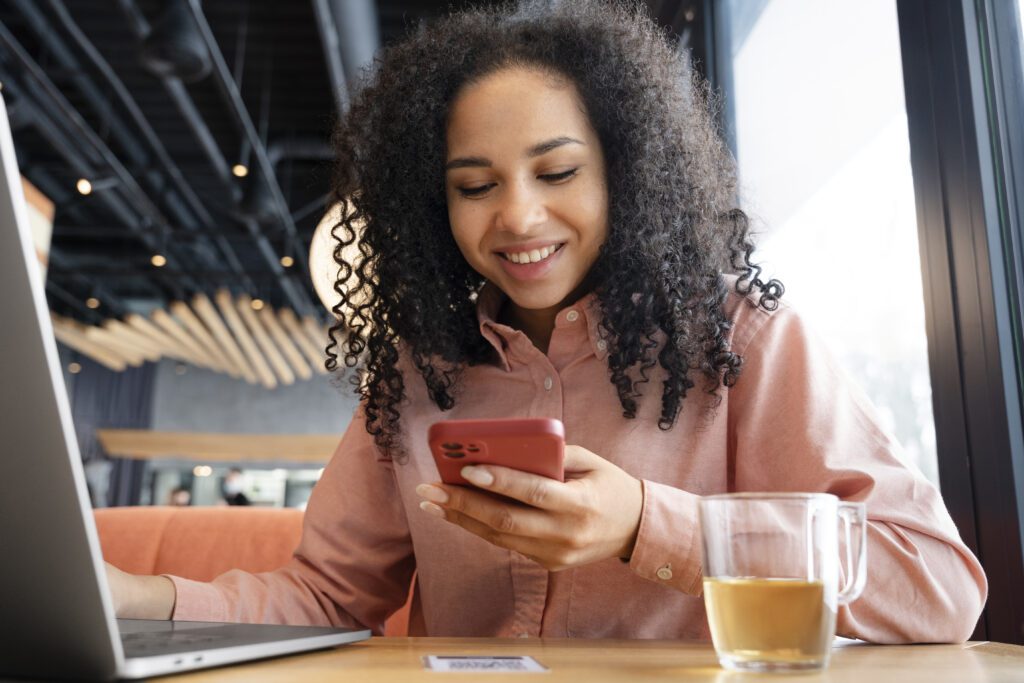Mulher negra olhando para celular.